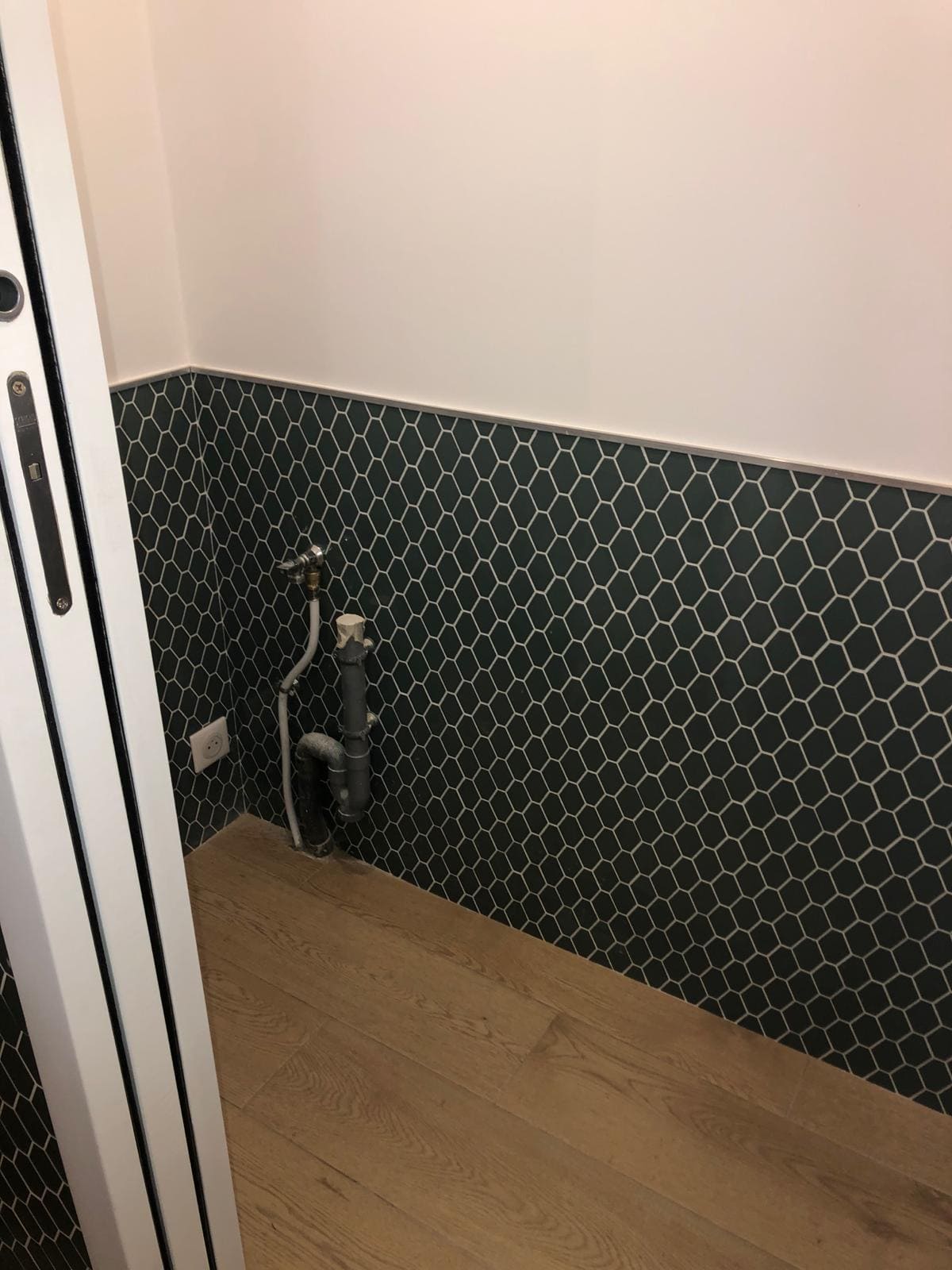 Une pèce avec un parquet, du carrelage à mi hauteur des murs