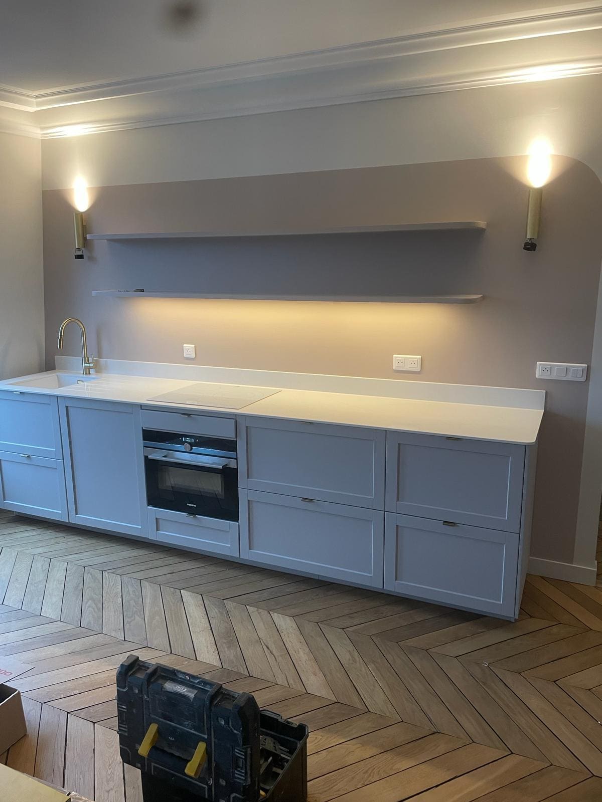 Une cuisine avec des tiroirs, un four et un parquet ancien
