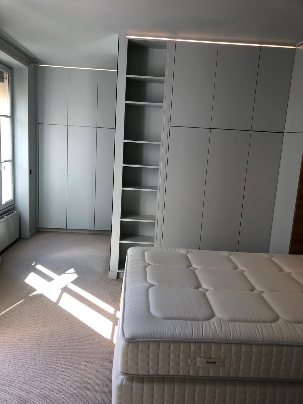 Une chambre avec de la moquette, un lit et des placards gris