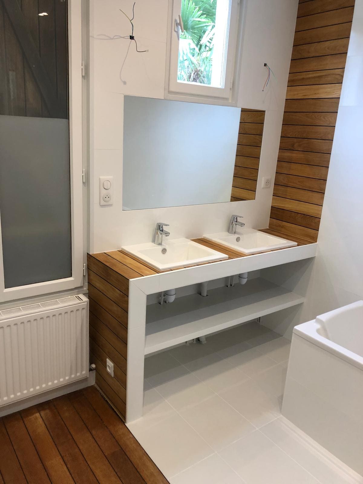 Une salle de bain avec une baignoire, deux lavabos et un miroir