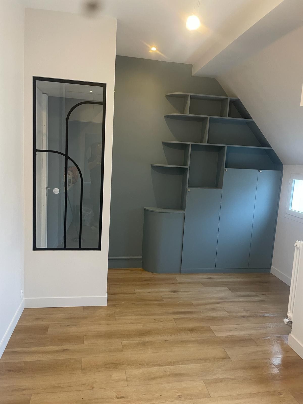 Une pièce avec une vitre, et des rangements peints en bleu