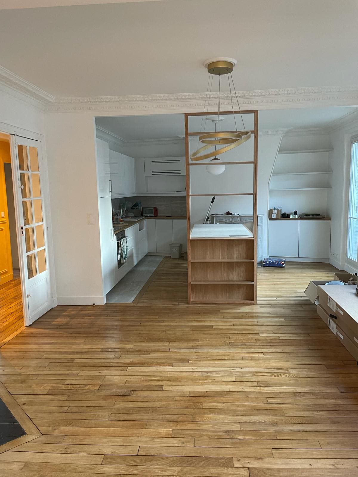 Un salon avec un parquet et une cuisine en blanche
