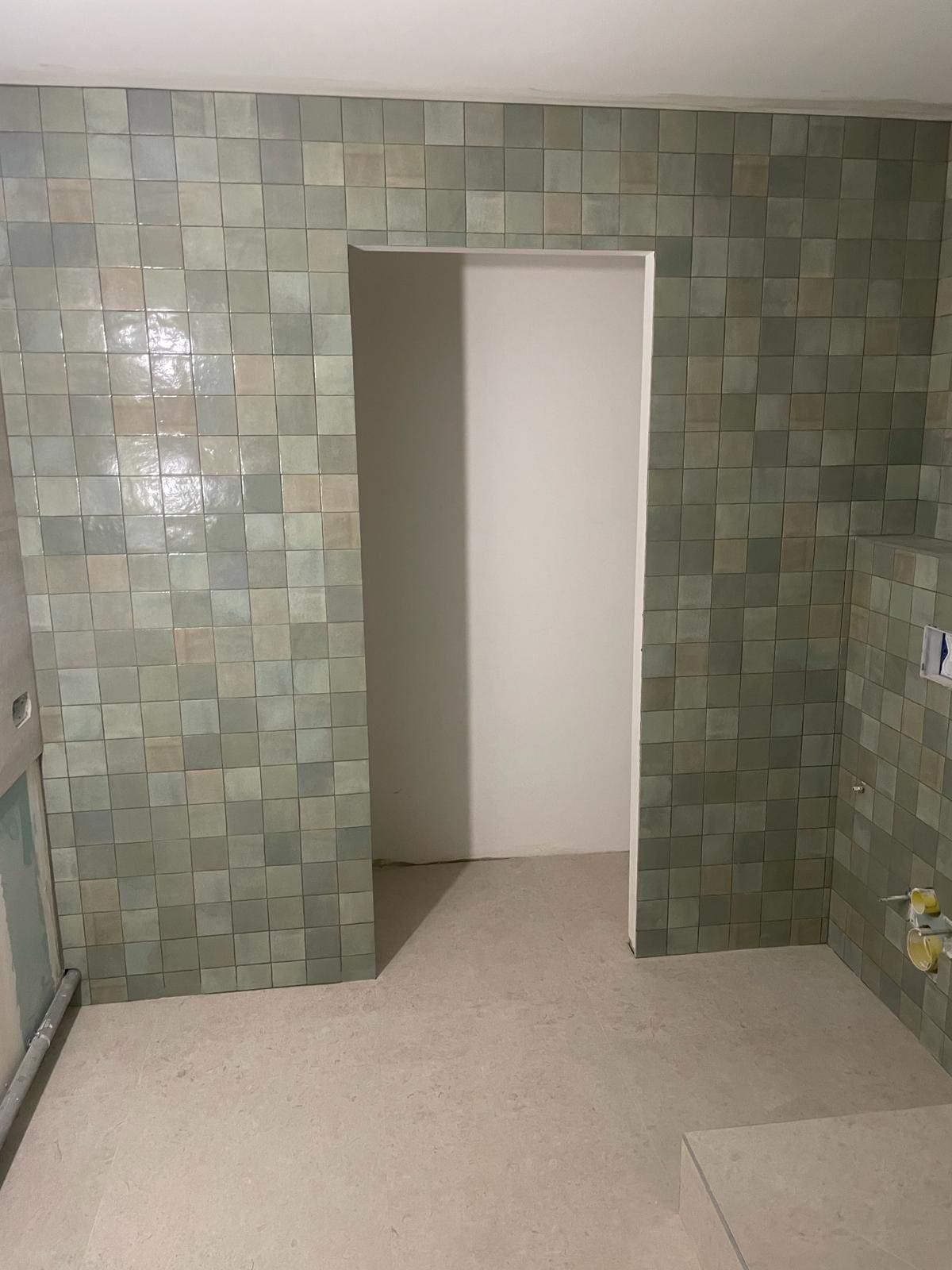 Une pièce avec du carrelage vert sur les murs