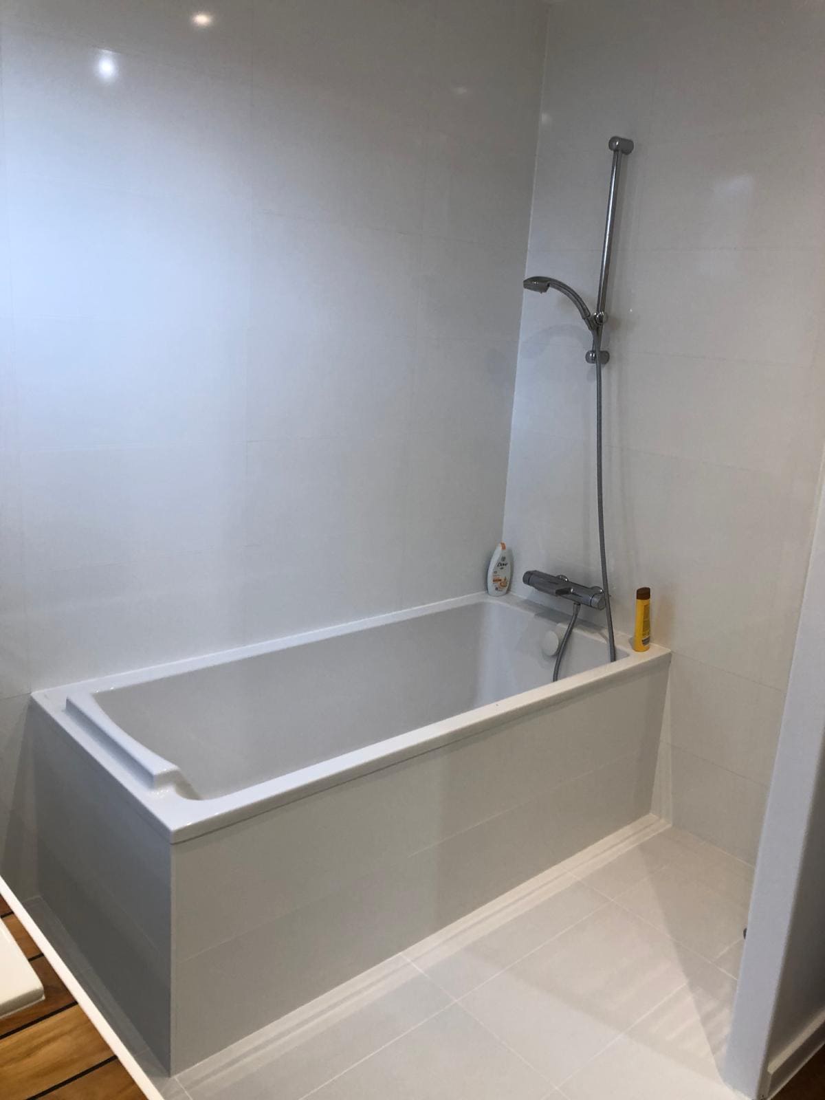 Une salle debain avec une baignoire et du carrelage blanc sur les murs